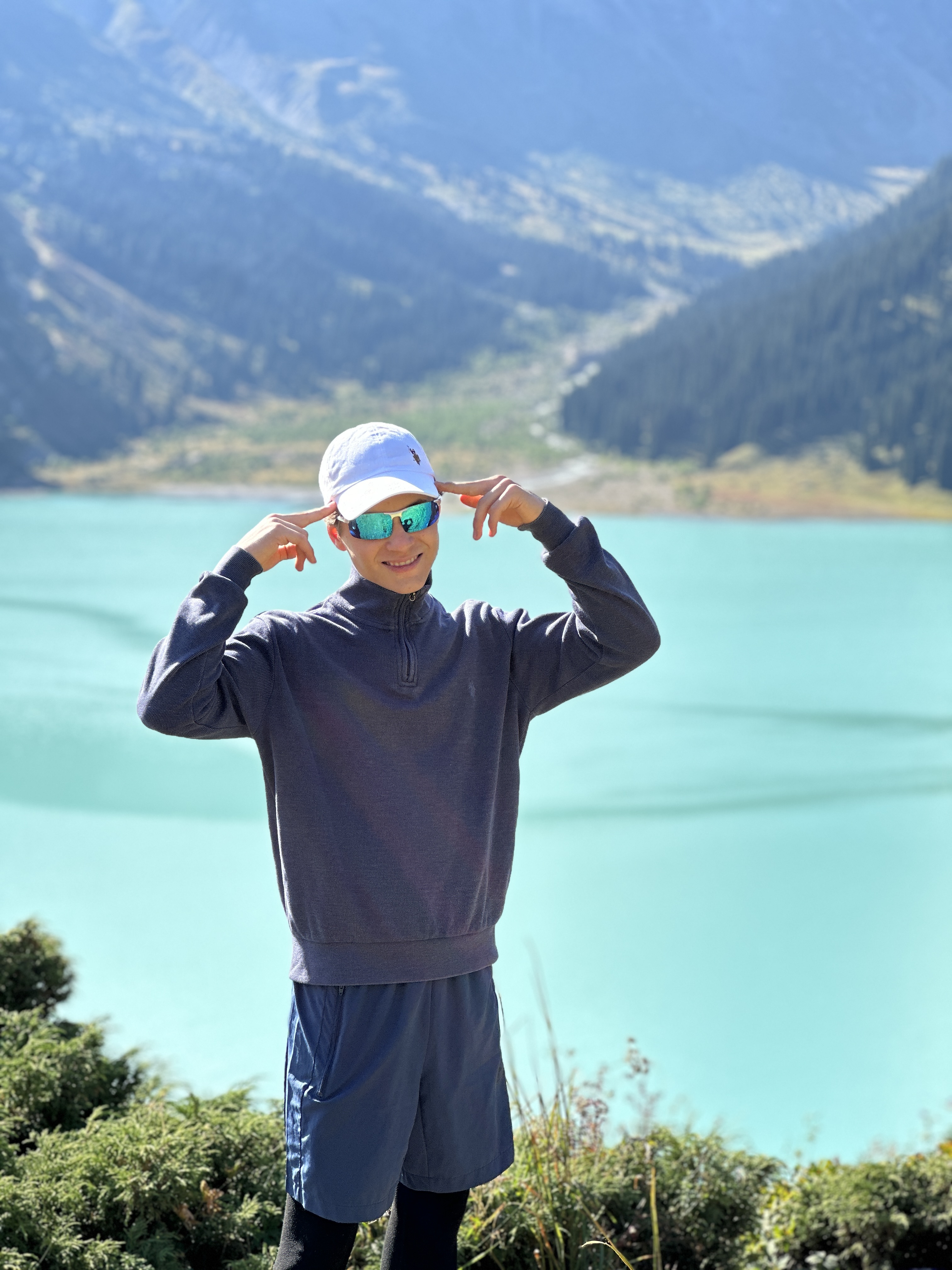 Traveller smiling in front of the turquoise Big Almaty Lake